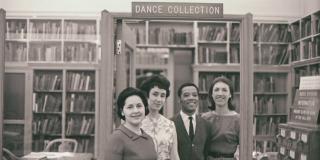 Four staff members (three women and one African American men) smile at the camera in a historic photo of the dance collection, now known as the Jerome Robbins Dance Division