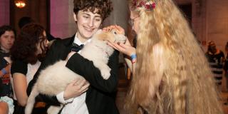 Photo from NYPL's Anti-Prom featuring two teens smiling at a puppy