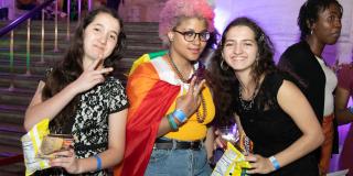 Photo from NYPL's Anti-Prom featuring teens posing for camera with rainbow flag