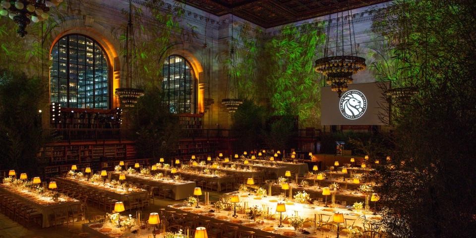 Rose Main Reading Room during a nighttime benefit event with decorated tables and greenery projected onto the walls.