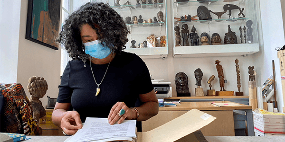 A scholar at the Schomburg Center looks through a folder in a room full of artifacts. 