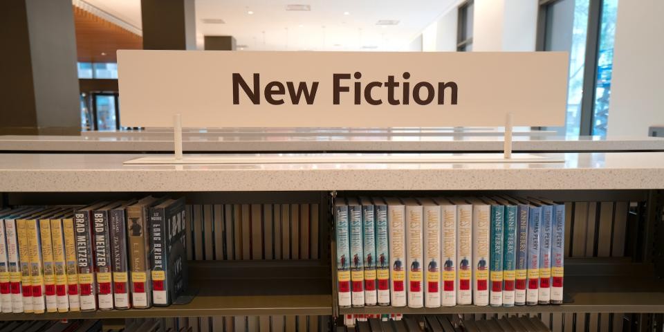 Interior of a library with a bookshelf displaying a sign for new fiction.