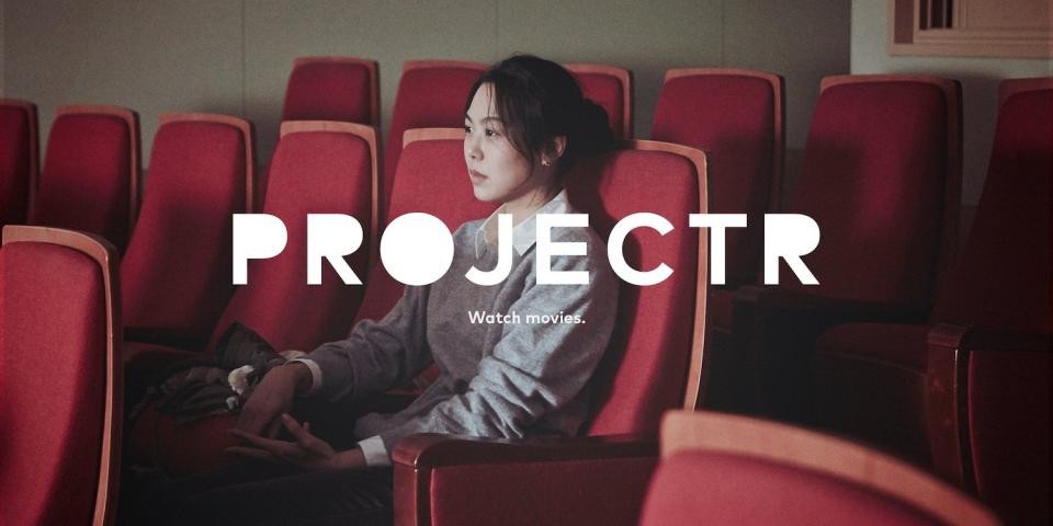 A still from a movie starring Kim Min-hee sitting in a movie theater with a white text Projectr logo superimposed over the image.