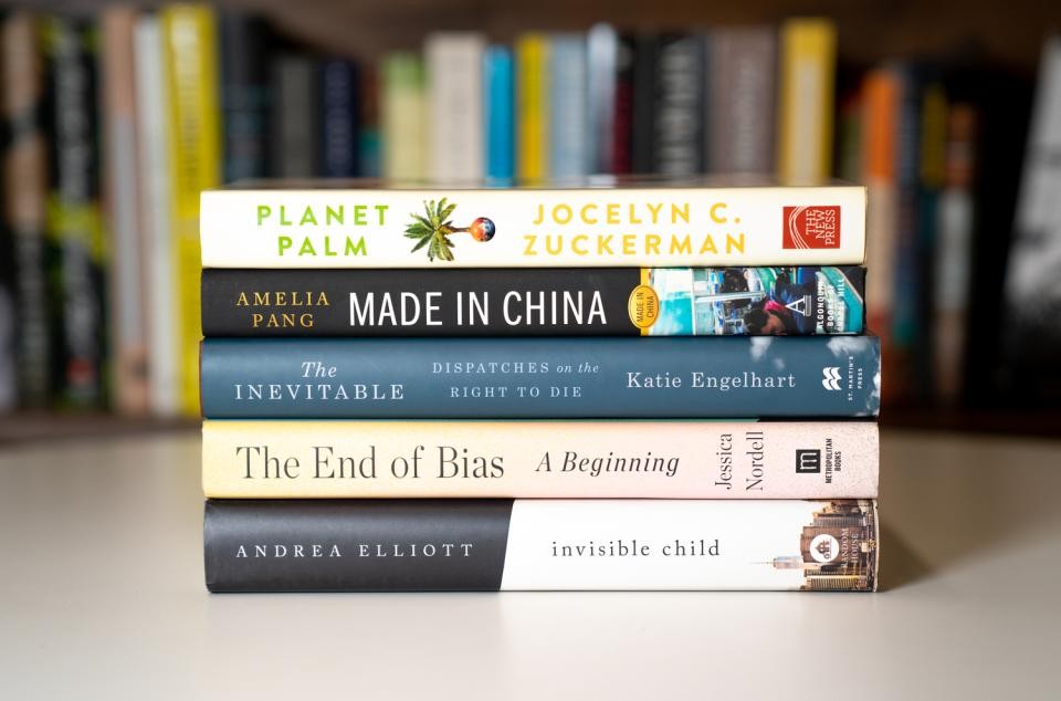 Stack of books on a table in front of a bookshelf with titles that include: Planet Palm, Made in China, The End of Bias, Invisible Child.
