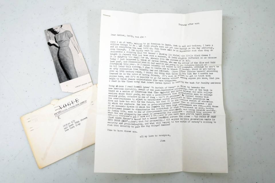 A typed letter and envelope and photo of a woman in a dress from a magazine