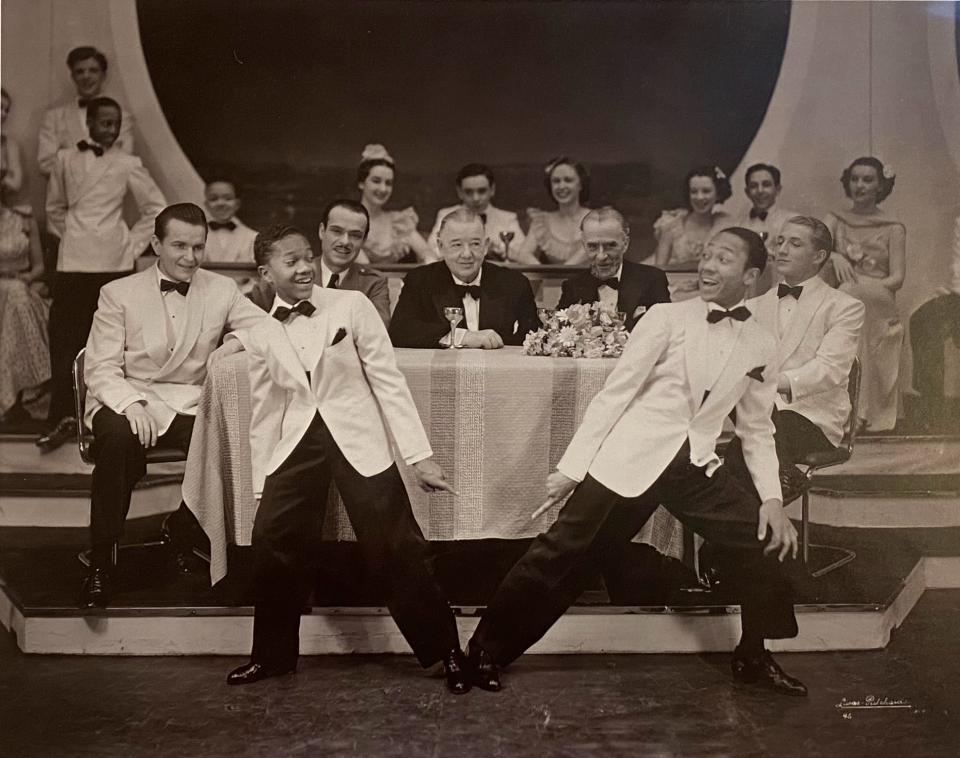 two boys dancing in front of a bunch of people sitting at a table.