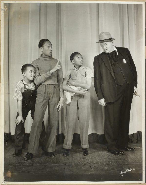 Three Black boys stand next to a white man in a suit