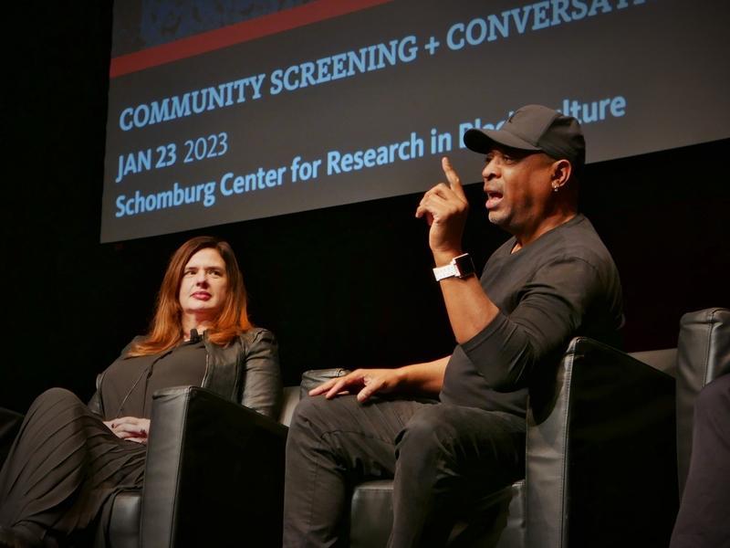 Two people are seated on stage at the Schomburg Center. 