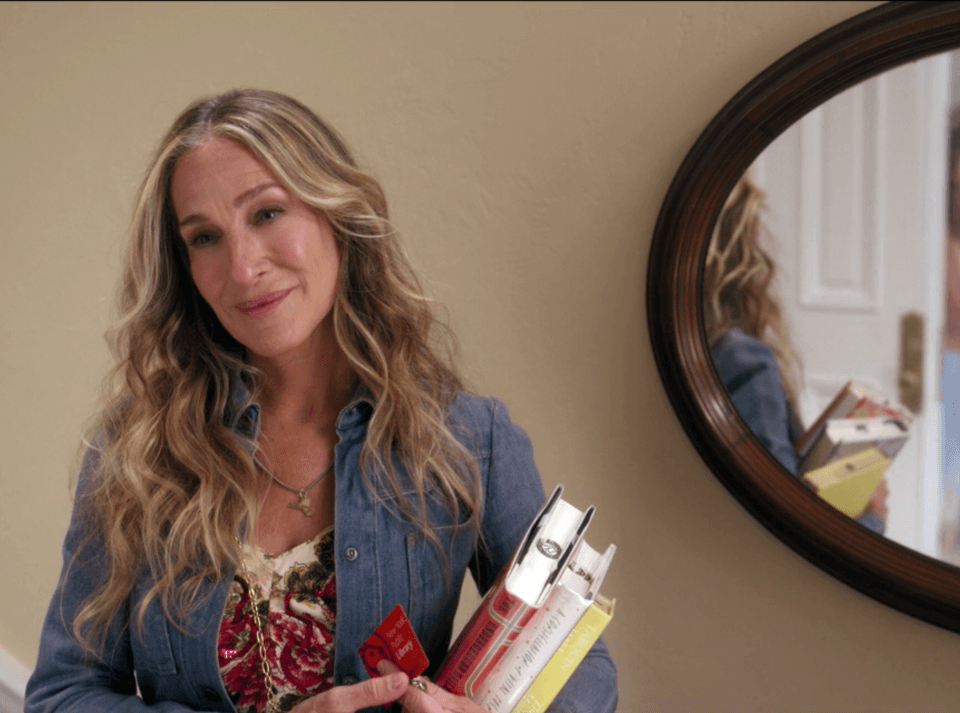 Sara Jessica Parker as Carrie Bradshaw holding a NYPL library card and three books