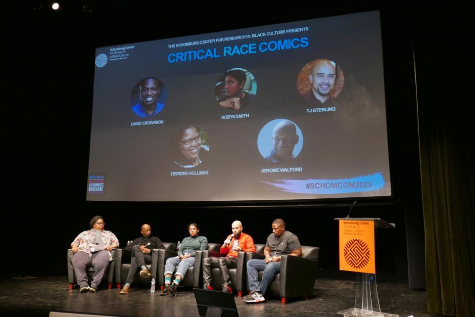 A wide shot of David Crownson and four fellow panelist on stage at Schomburg Center. All are sitting on dark gray chairs.