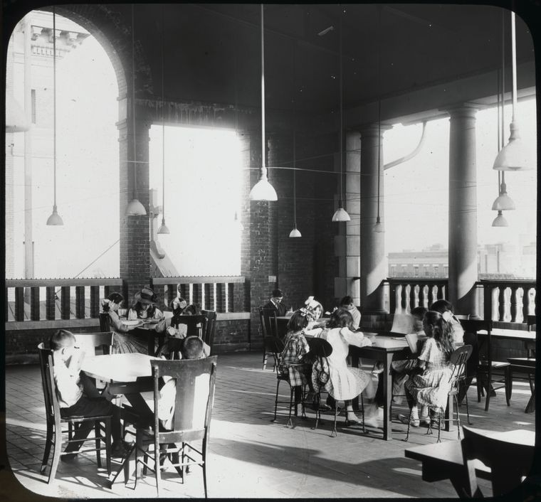 Children reading on the roof of a library, pendant lights hanging down above them