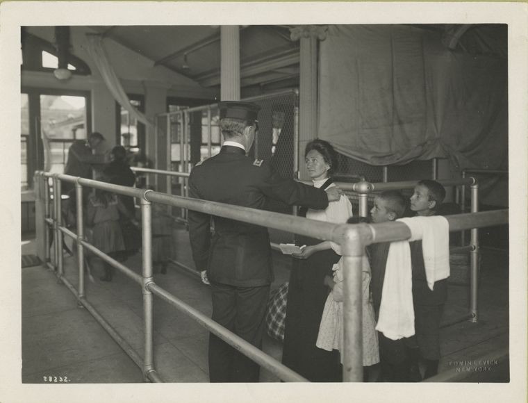 Mother with three young children waiting in medical line while official stands by. 