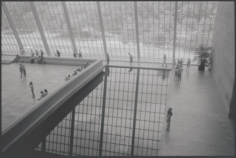 interior of the Met Museum showing a room with a tall wall of windows and a reflecting pool