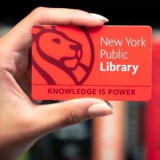Photo of a hand holding a red NYPL card that reads: New York Public Library, Knowledge Is Power
