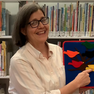Librarian holding up craft featuring multicolored birds.