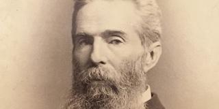 Herman Melville is pictured looking sternly through shoulder length wiry beard in a sepia toned photograph