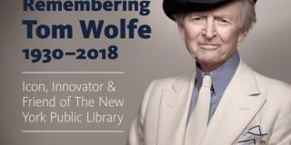 Tom Wolfe is seen in a cream colored suit, smiling with a dark fedora 