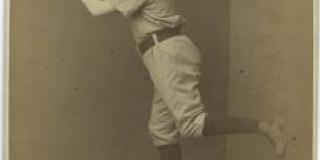 An 1885 albumen silver print of baseball player Jim Fogarty turning, one leg outstretched, and throwing a ball in the air. 