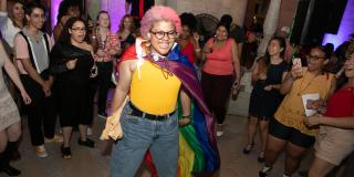 Photo from NYPL's Anti-Prom featuring a smiling teen wearing a rainbow flag