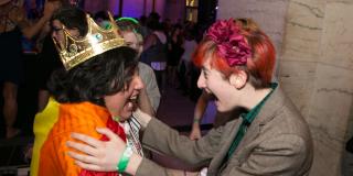 Photo from NYPL's Anti-Prom featuring two teens, one with a crown and rainbow flag, the other with flowers in their hair