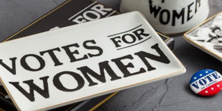 Photo of "Votes for Women" items from the Library Shop, including a lapel pin, mug, and tray