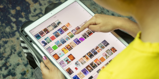 Photo of a person holding an iPad with the SimplyE app on screen displaying a bunch of small book covers