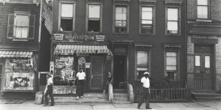 Historic black-and-white photograph of several people standing outside of a storefront in Brooklyn