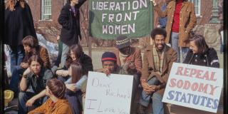 Color photo of a goup of men and women holding various signs: "GAY LIBERATION FRONT WOMEN" "REPEAL SODOMY STATUTES" "DEAR RICHARD, I LOVE YOU, WILLIE"