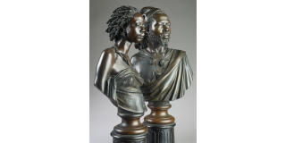Photo of two bronze busts positioned on columns: one of a Black man, the other of a Black woman, both gazing off into the distance