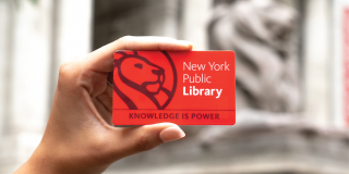 Photo of a hand holding a red NYPL library card that reads: New York Public Library, Knowledge Is Power