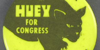 Closeup photo of a historic button with a neon yellow background depicting an illustration of a black panther with bold neon yellow text that reads: Huey for Congress