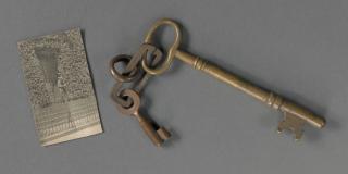 Photo of a historic photograph next to a very old key on a chain