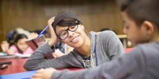 Photo of a woman with glasses helping a young student with schoolwork. 