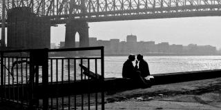 Two men seated on the waterfront near the Queensboro Bridge.