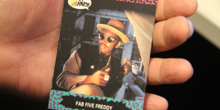 A hand holding a trading card with Fab Five Freddy on the cover