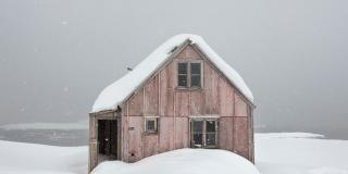 Image of cabin in an snowy environment, with its roof covered in snow.