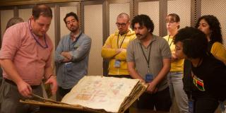 Residency participants look at a large book of maps.