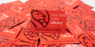 Scattered pile of red library cards that read: New York Public Library above and Knowledge Is Power below.