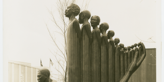 Sepia-toned photograph of Augusta Savage's sculpture Lift Every Voice and Sing (Harp), which features a line of people of various heights standing close together so they resemble a harp.
