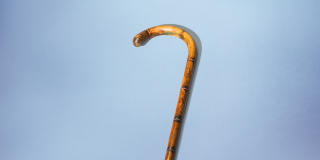 Slender walking stick with a curved handle, made of light-colored wood