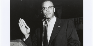 Photograph of Malcolm X speaking at a Marcus Garvey Day Celebration by Cecily Layne