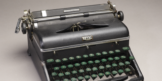 Black typewriter with green keys and “Royal” logo.