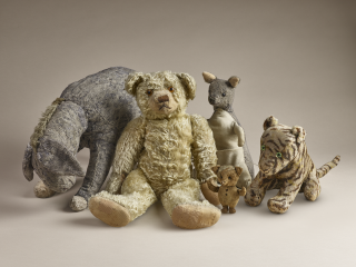 Photo of five stuffed Winnie the Pooh and friends toy animals ranging in size from teddy bear—just over a foot high—to toy piglet—less than 5 inches high. 