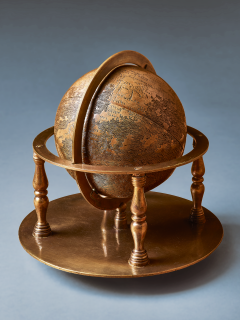 Small bronze globe encircled by a ring that attaches it to a circular base