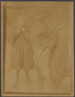 A faded black and white image of two girls wearing dresses, one of them bending with a cricket bat leaning against the ground