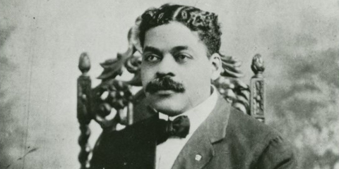 A headshot of Arturo Schomburg seated in a chair. 