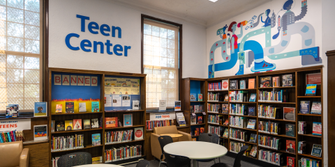 Interior of the West New Brighton Library Teen Center, featuring work areas and walls of books.